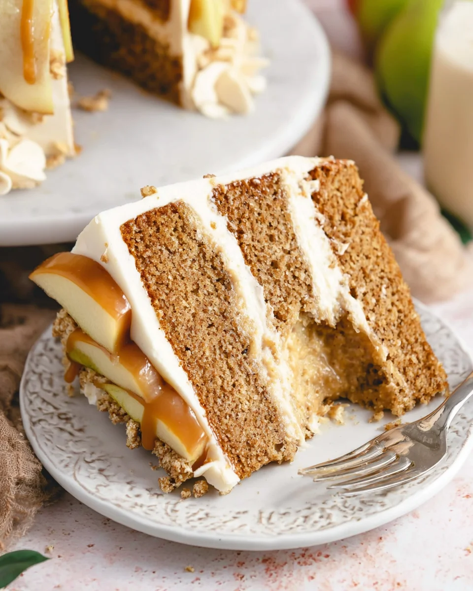 A slice of Caramel Apple Layer Cake on a small plate with a bite taken out of it.