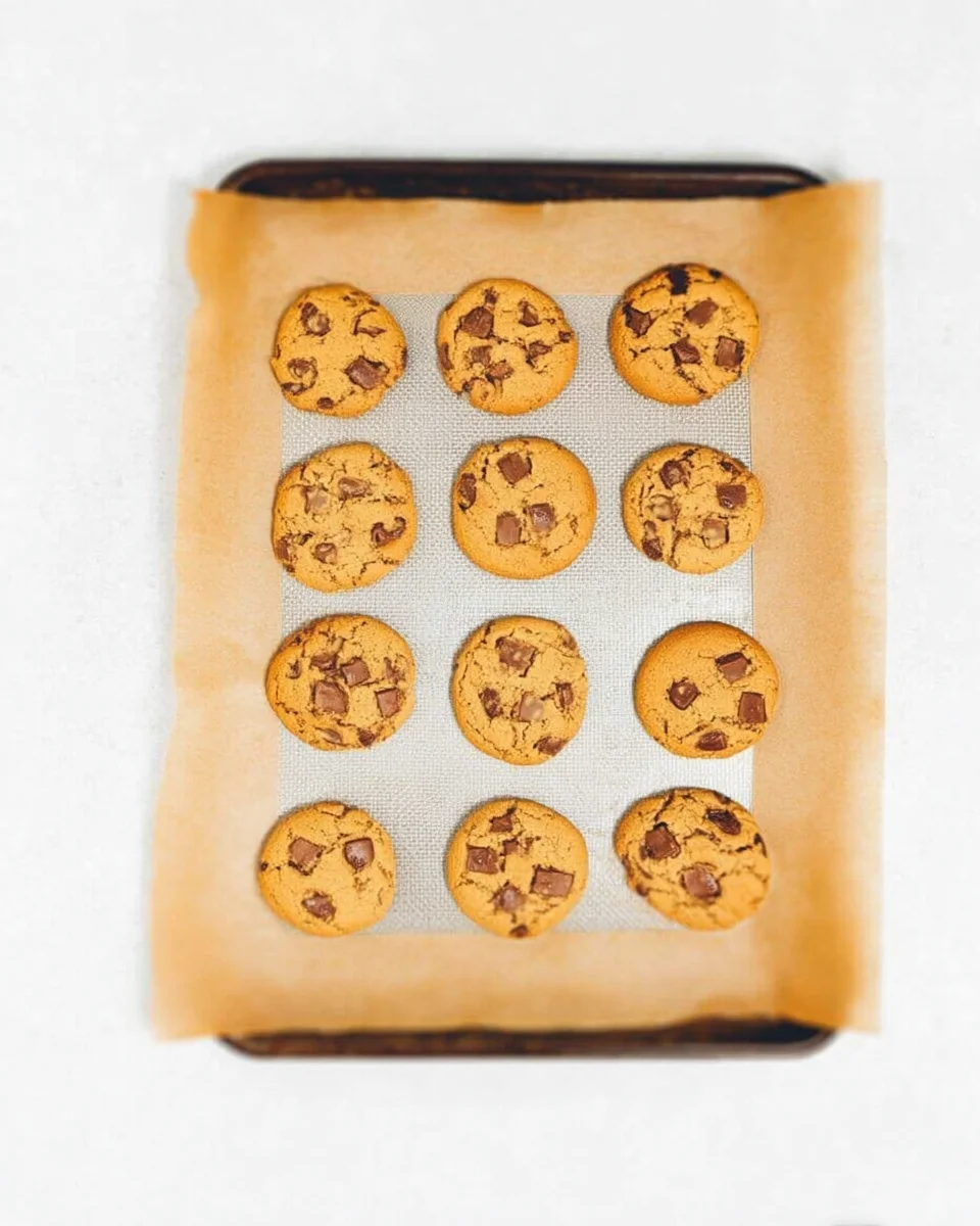 Peanut butter chocolate chip cookies freshly out of the oven on a silicone baking mat on a baking sheet. Peanut butter chocolate chip cookies freshly out of the oven on a silicone baking mat on a baking sheet.
