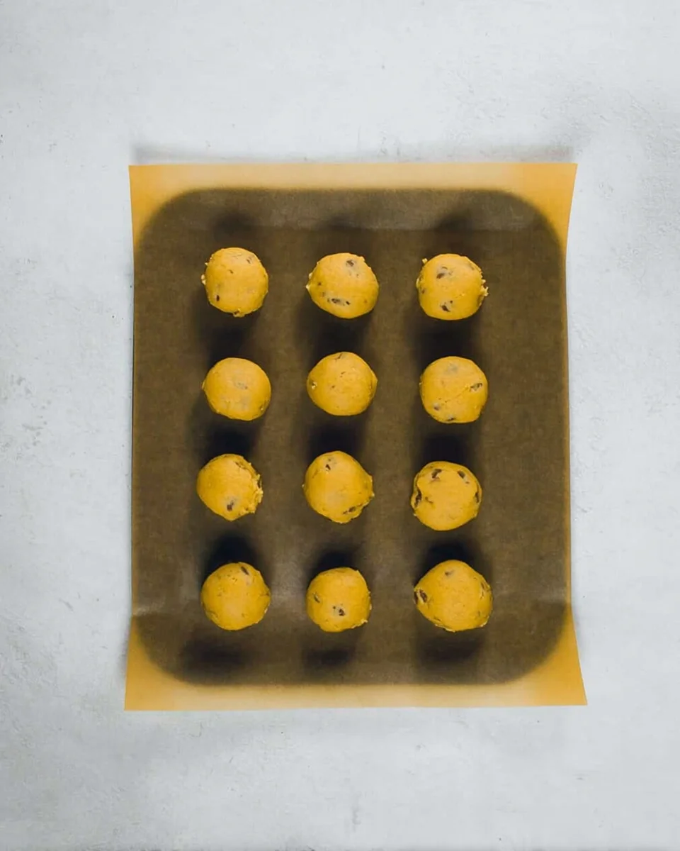 Cookie dough balls on parchment paper on a baking sheet.