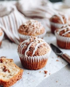 Close-up of a moist coffee cake muffin with crumb topping and vanilla glaze drizzle.