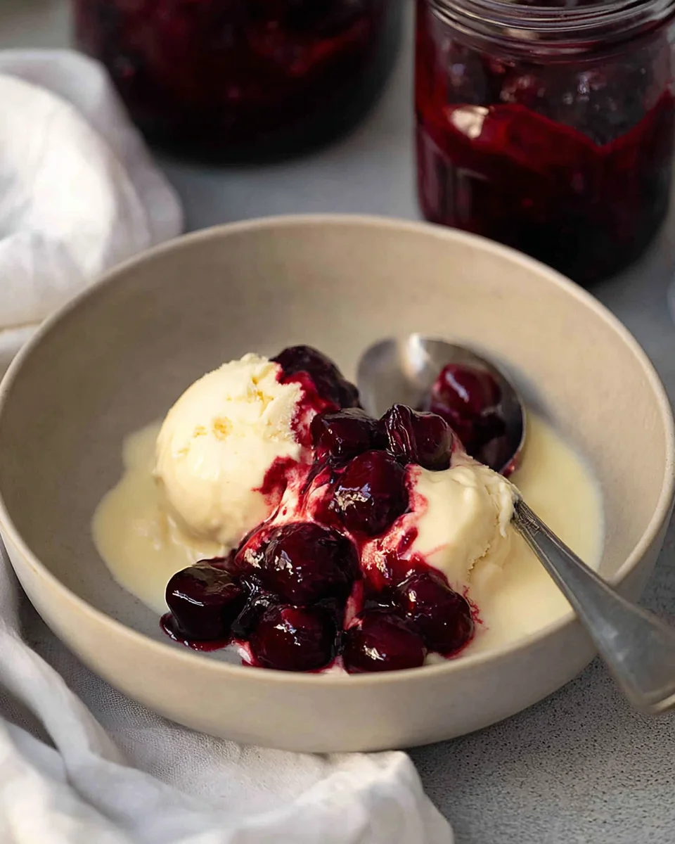 Bowl of vanilla ice cream served with cherry pie filling on top.