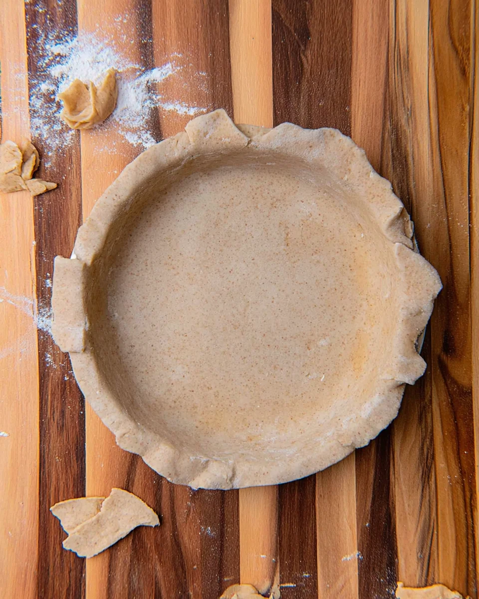Pie crust with trimmed edges resting inside a pie plate.