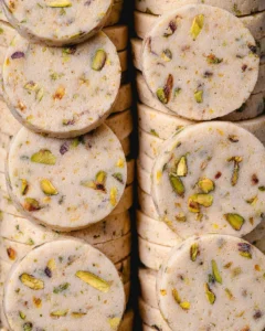 Pistachio shortbread cookies lined up in two rows on a green rectangle platter