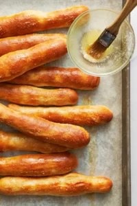 a pan of breadsticks fresh from the oven, being brushed with garlic butter.