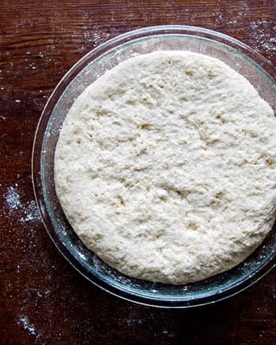 Brioche dough risen, filling up a large glass bowl. 