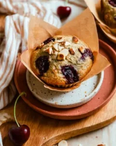 pistachio cherry muffins in parchment liner on speckled serving plate.