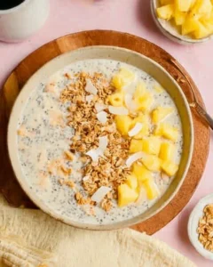 pineapple overnight oats topped with granola, pineapple slices and shredded coconut.