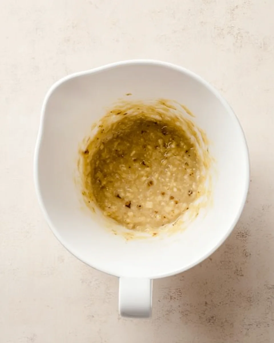 wet ingredients for peanut butter banana muffins in white mixing bowl.