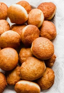 Freshly fried doughnuts on a tray.