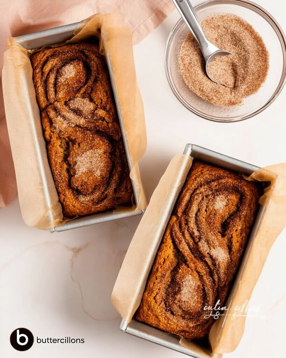 Cinnamon sugar swirled on top of pumpkin bread batter in mini loaf pans.