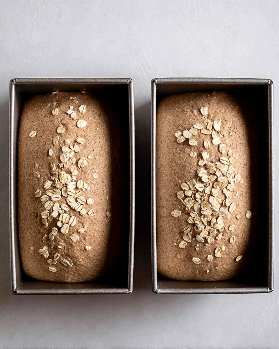 Two bread pans filled with outback bread dough. 