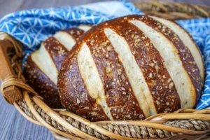 Two loaves of Pretzel Bread in a wooden basket with a blue towel.