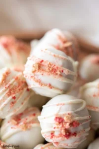 white chocolate drizzled strawberry cheesecake truffles.
