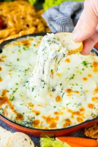 A slice of bread scooping up a serving of spinach artichoke dip.