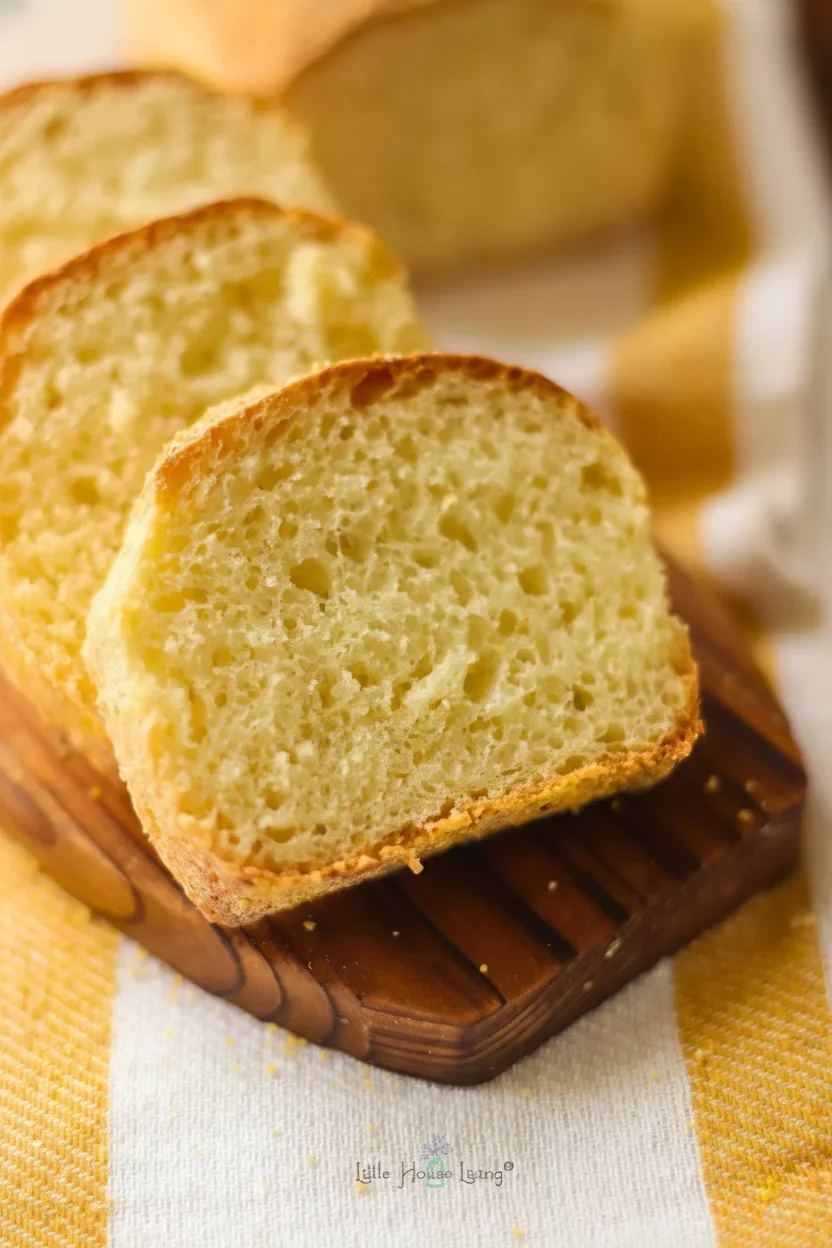 14-2.jpg Close-up of a soft, golden bread slice on a wooden cutting board with a blurred loaf in the background.