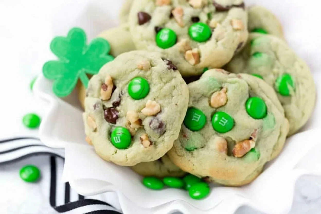 Green mint-flavored cookies with M&M candies and chopped nuts on white paper, festive and colorful.