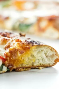 Close-up of a pizza slice showing a fluffy crust, melted cheese, and toppings.