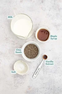 Ingredients for vanilla chia seed pudding in small bowls: milk of choice, chia seeds, maple syrup, vanilla extract, salt