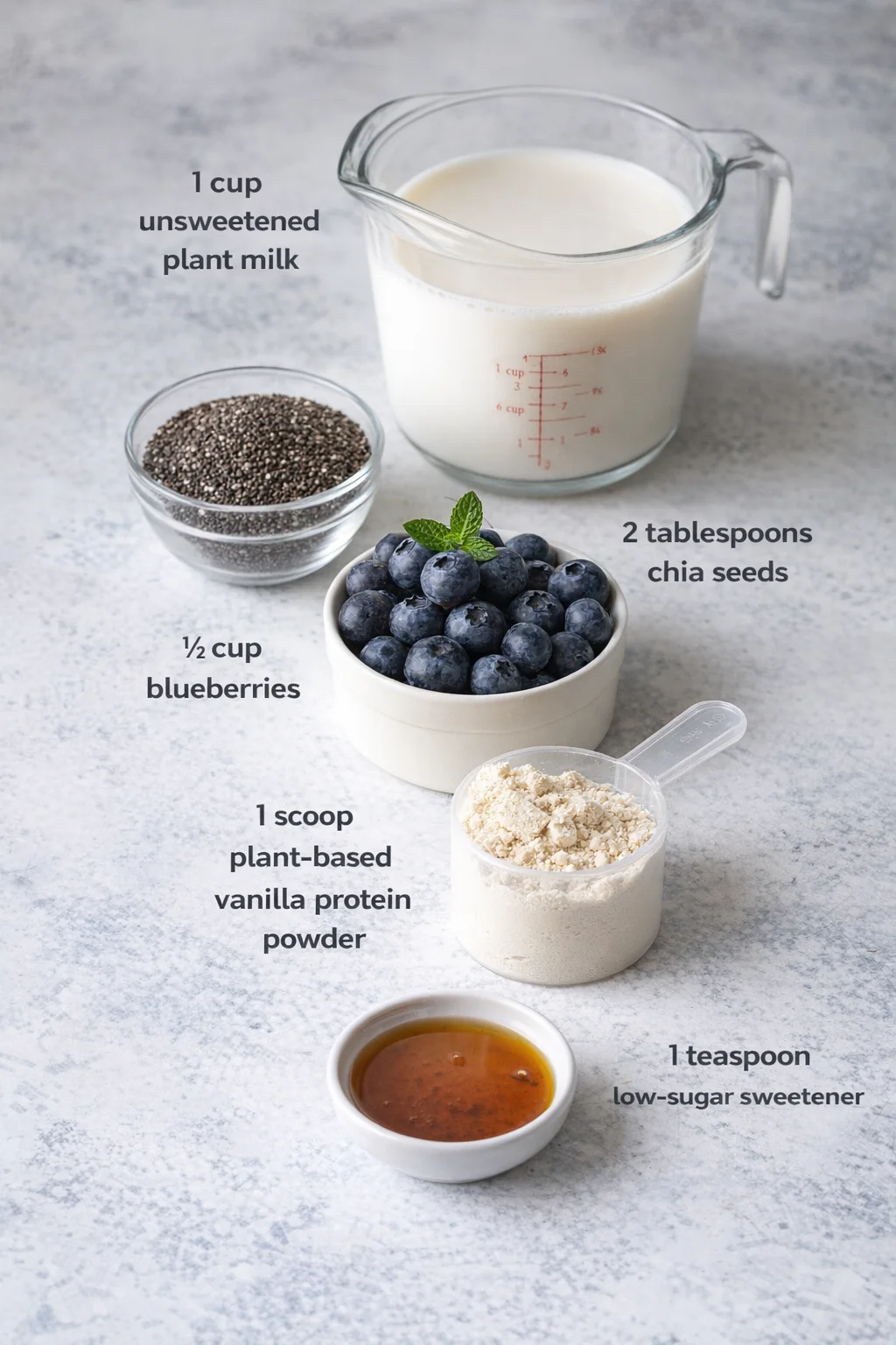 Measured ingredients arranged for 5-Ingredient Blueberry Chia Protein Pudding (No-Bake & Low Sugar): 1 cup unsweetened plant milk (almond or soy work great), 2 tablespoons chia seeds, ½ cup fresh or frozen blueberries, 1