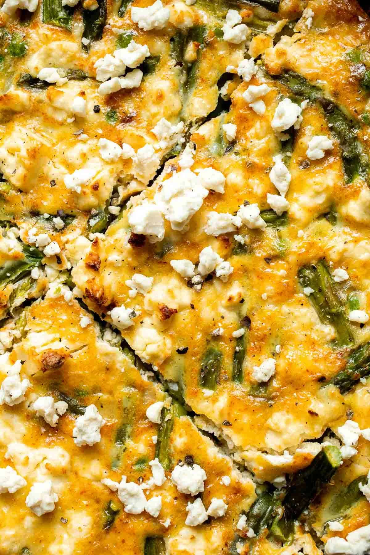 Homemade asparagus frittata with feta cheese on a white plate.