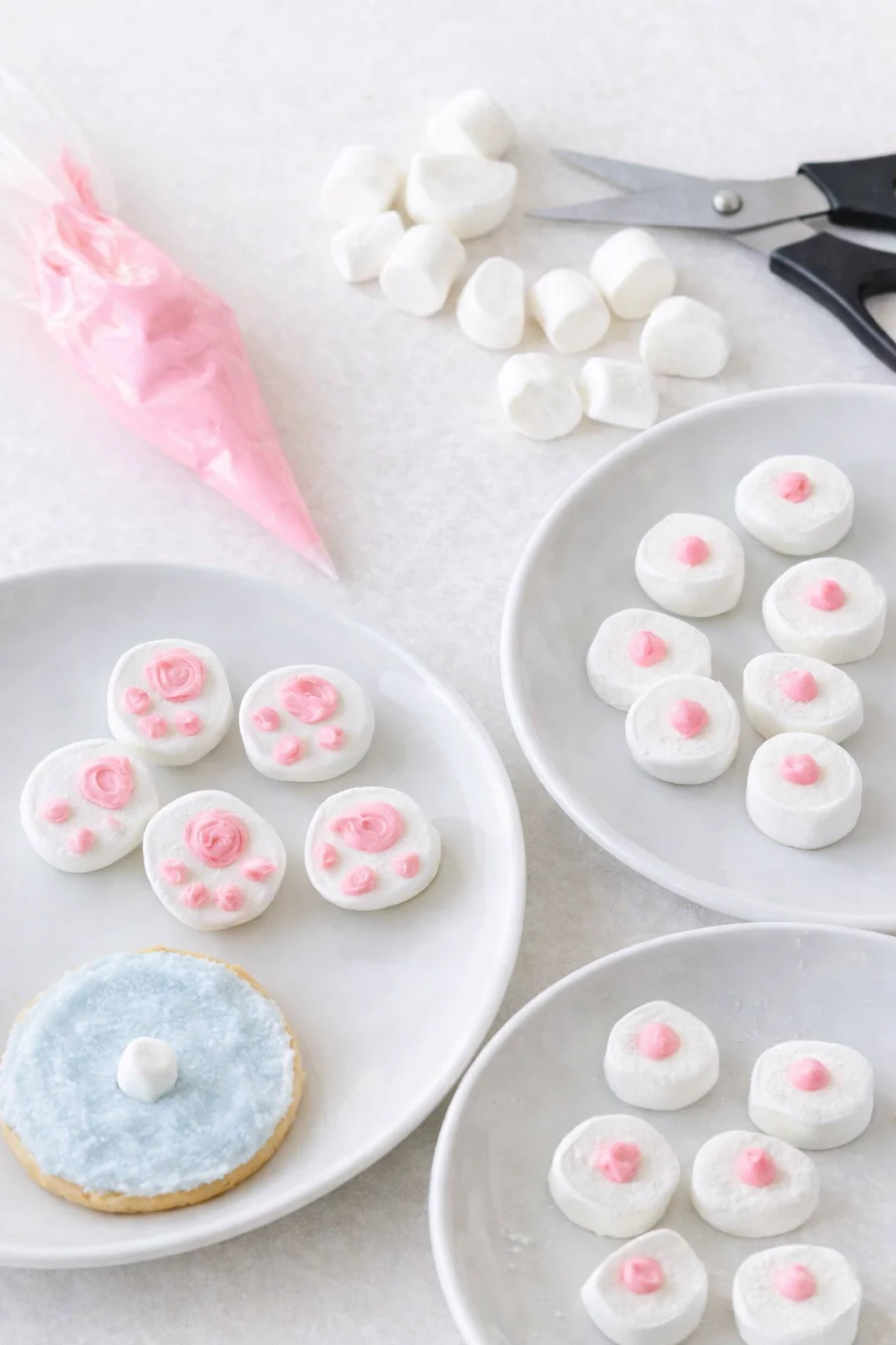 Halved marshmallows and a pink piping bag, tiny piped bunny feet on flat sides.