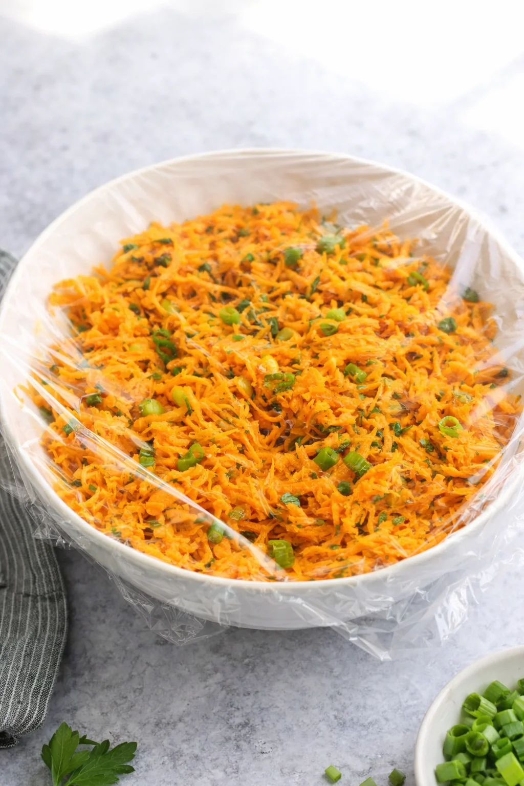 Bowl covered with plastic wrap chilling in refrigerator, salad resting before serving.
