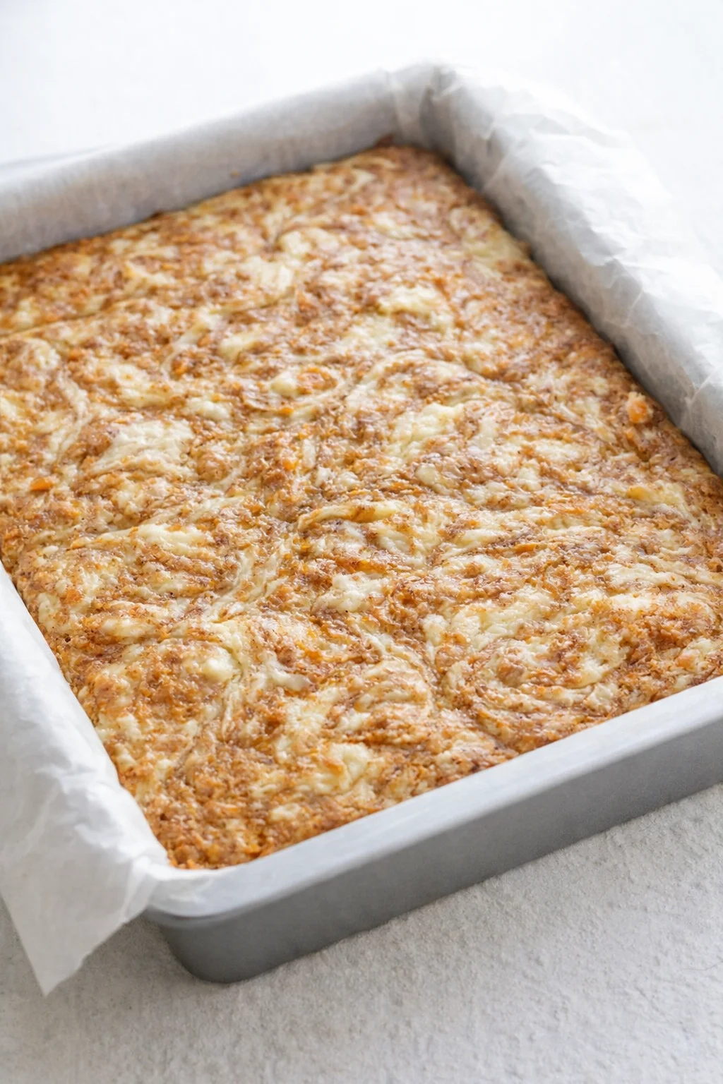 Baked bars with marbled swirls, golden edges and slightly jiggly center cooling in pan.