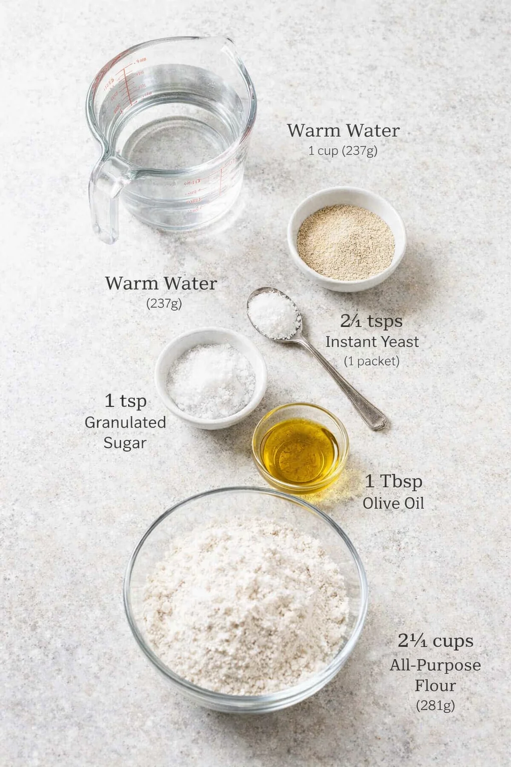 Measured ingredients arranged for Pita Bread: 1 cup warm water (237g), 2 1/4 teaspoons instant yeast (1 packet)*, 1 teaspoon granulated sugar, 1 teaspoon fine sea salt, 1 Tablespoon olive oil, 2 ¼ cups all-purpose flour 