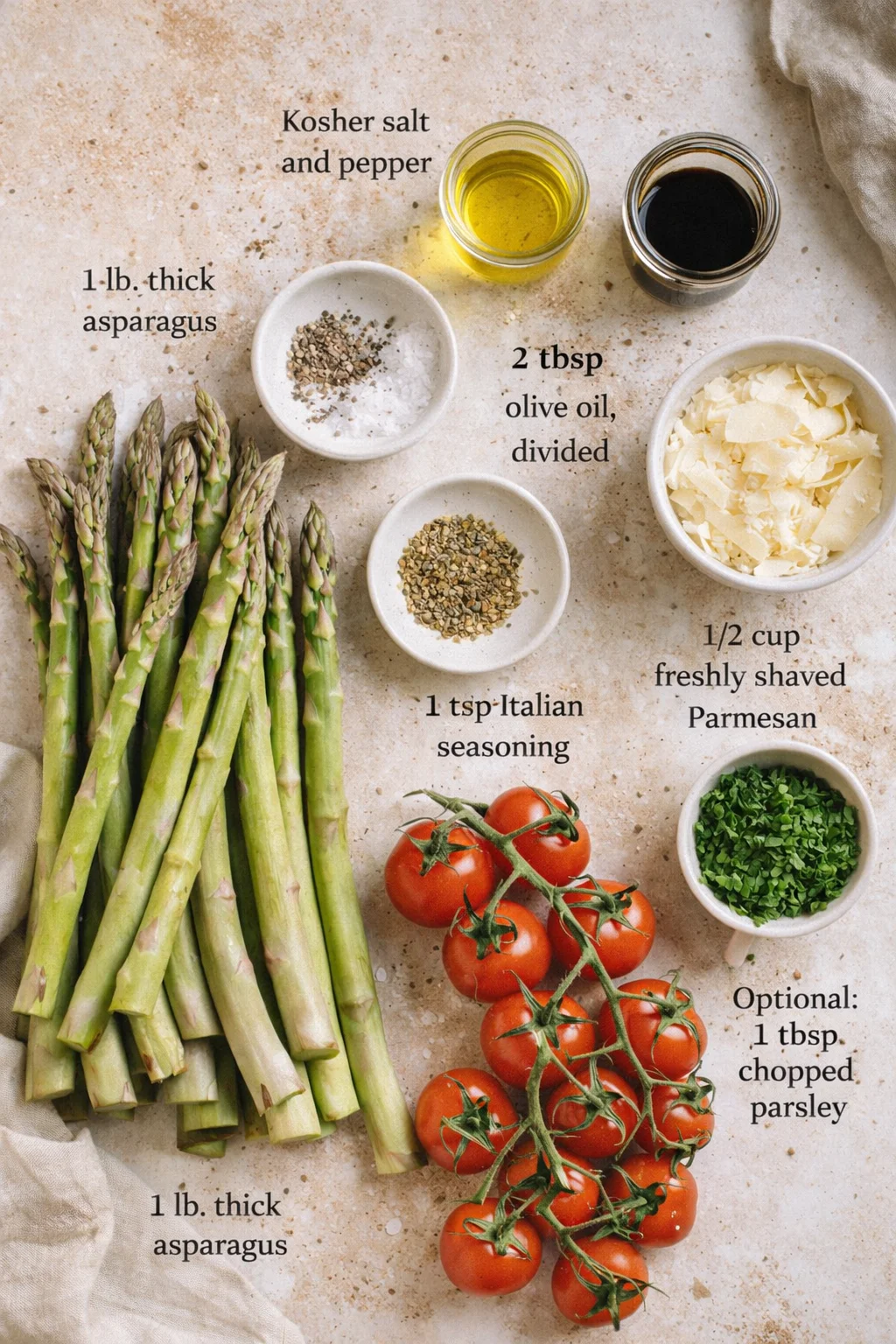 Overhead view of asparagus, tomatoes, and labeled bowls of oil, parmesan, and seasonings.