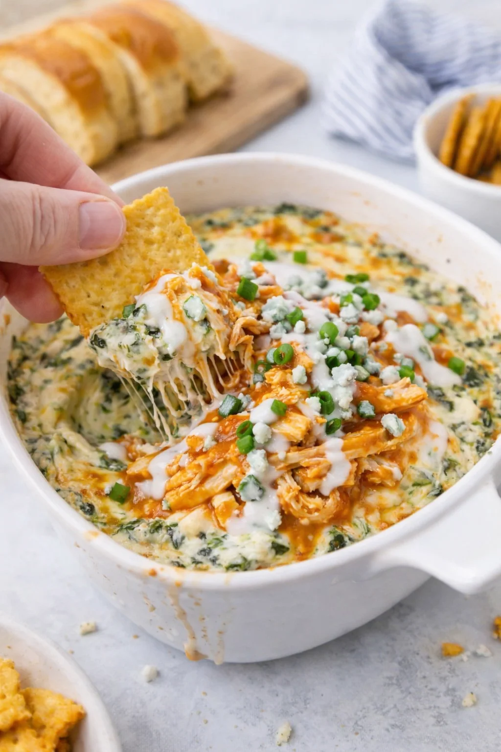 creamy spinach-artichoke dip topped with buffalo chicken, blue cheese, and chives, with a tortilla chip