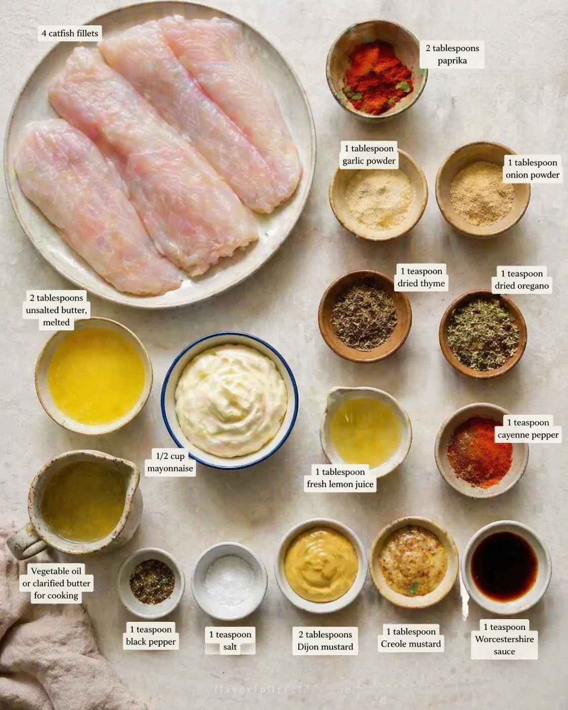 Overhead view of catfish fillets with labeled spices and sauce bowls for prep.