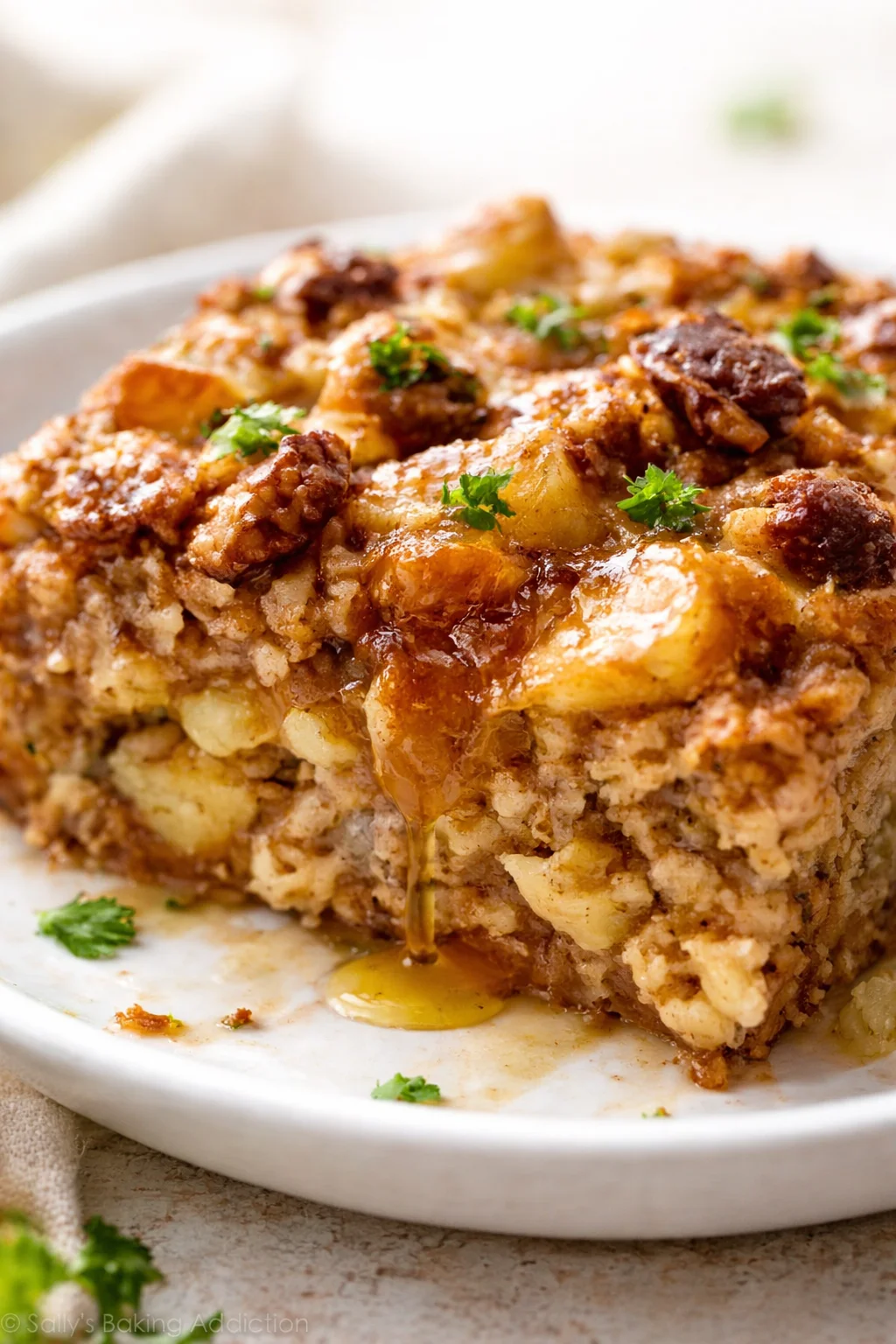 Close-up of a cheesy potato hash bake sliced on a white plate, garnished with parsley.