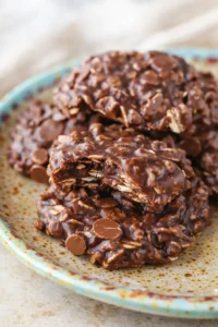 Close-up of chocolate-covered oat clusters on a speckled turquoise-rim plate