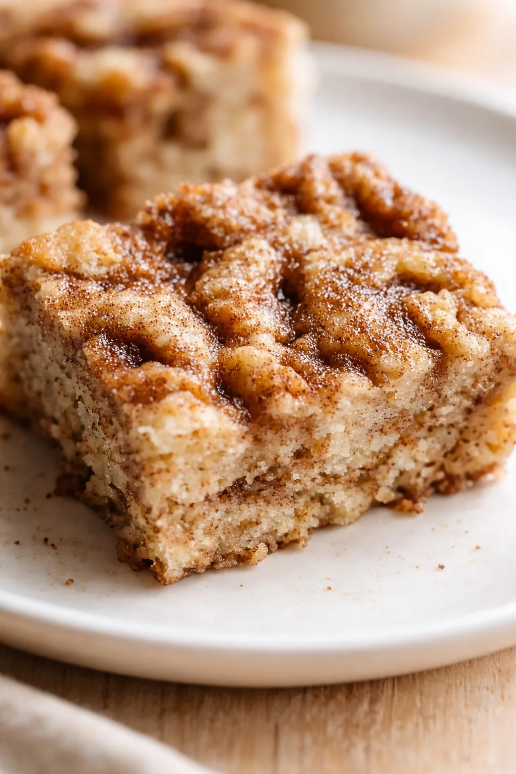 Close-up of a cinnamon-swirl coffee cake slice with a crumbly streusel topping on a white plate.