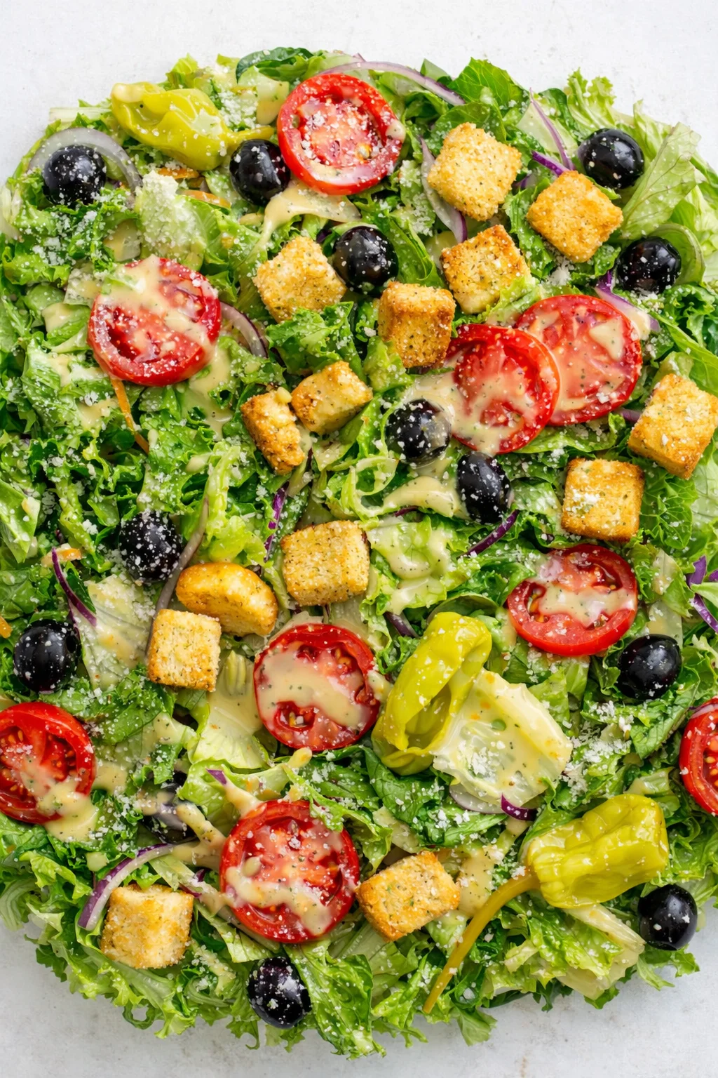 colorful chopped-green salad with cherry tomatoes, olives, red onions, croutons, and creamy dressing.