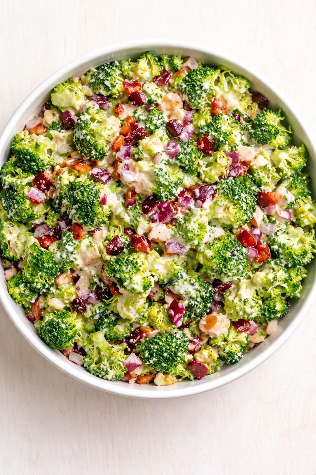 bowl of creamy broccoli salad with red onions and dried cranberries