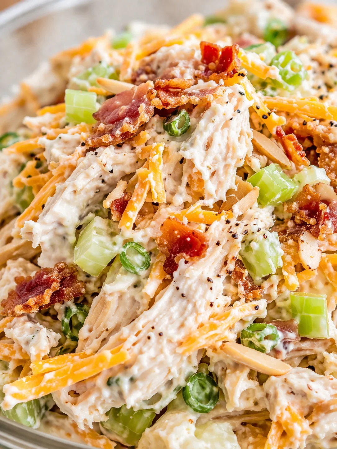 close-up of creamy chicken salad with celery, bacon, cheddar, and green onions in a bowl
