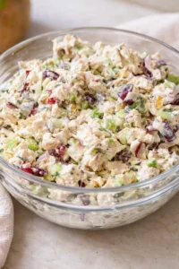 glass bowl of creamy chicken salad with celery, red grapes, and herbs