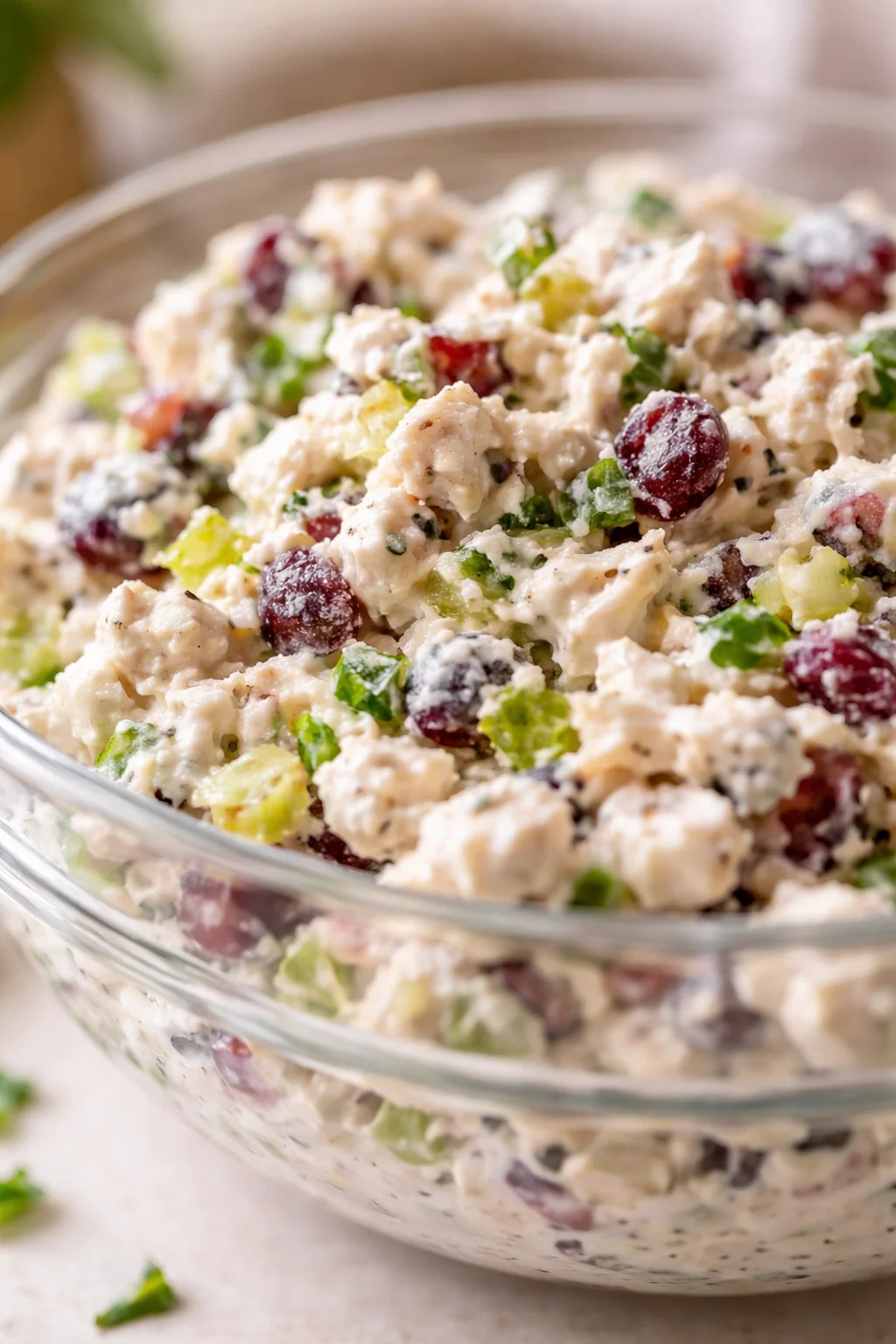 Creamy chicken salad with grapes, celery, and herbs in a glass bowl.