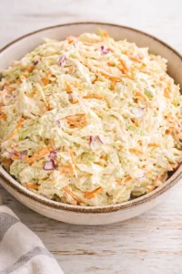 bowl of creamy coleslaw with shredded cabbage, carrots and red onion