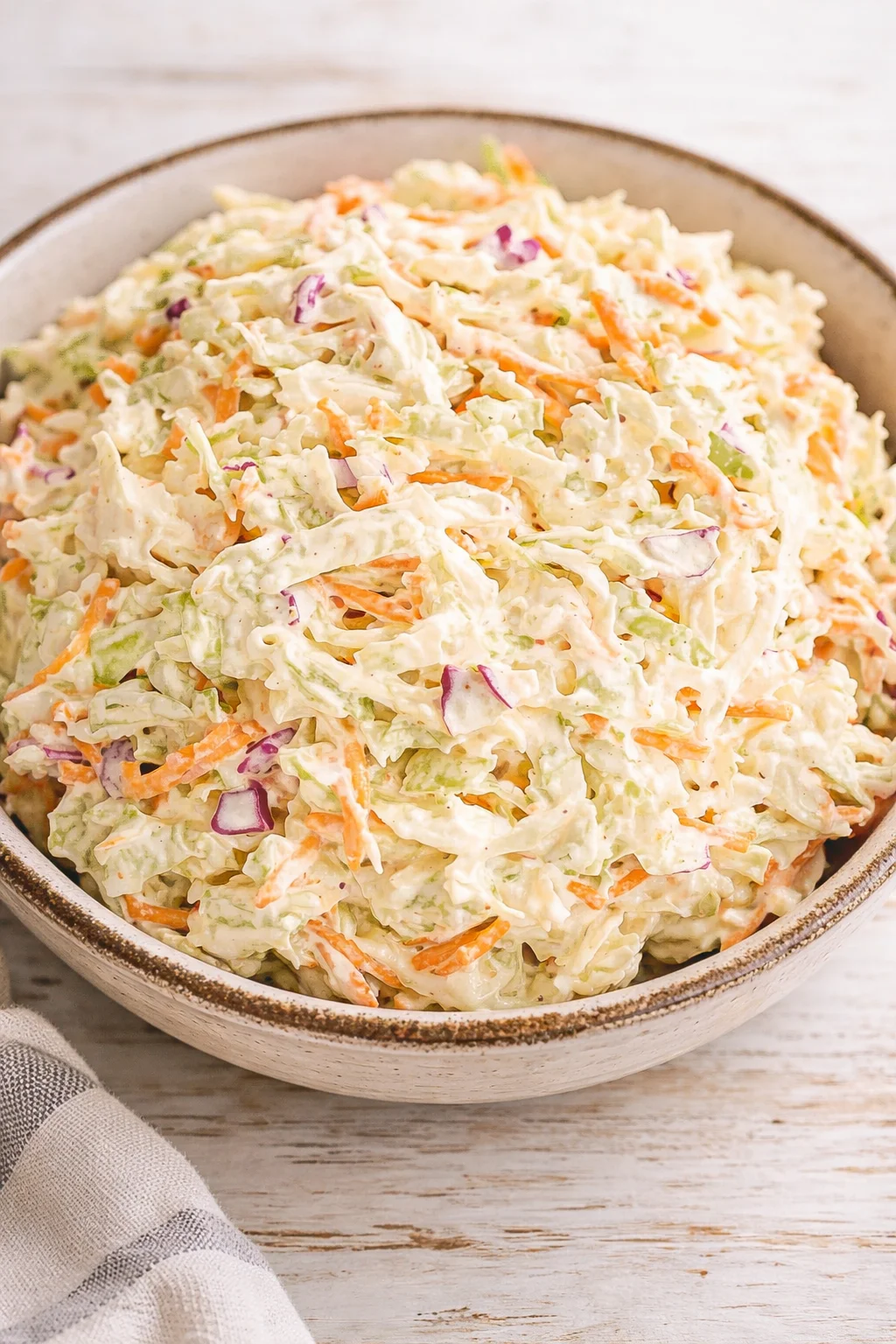 bowl of creamy coleslaw with shredded cabbage, carrots and red onion