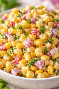 Creamy corn and purple potato salad with green onion in a white bowl