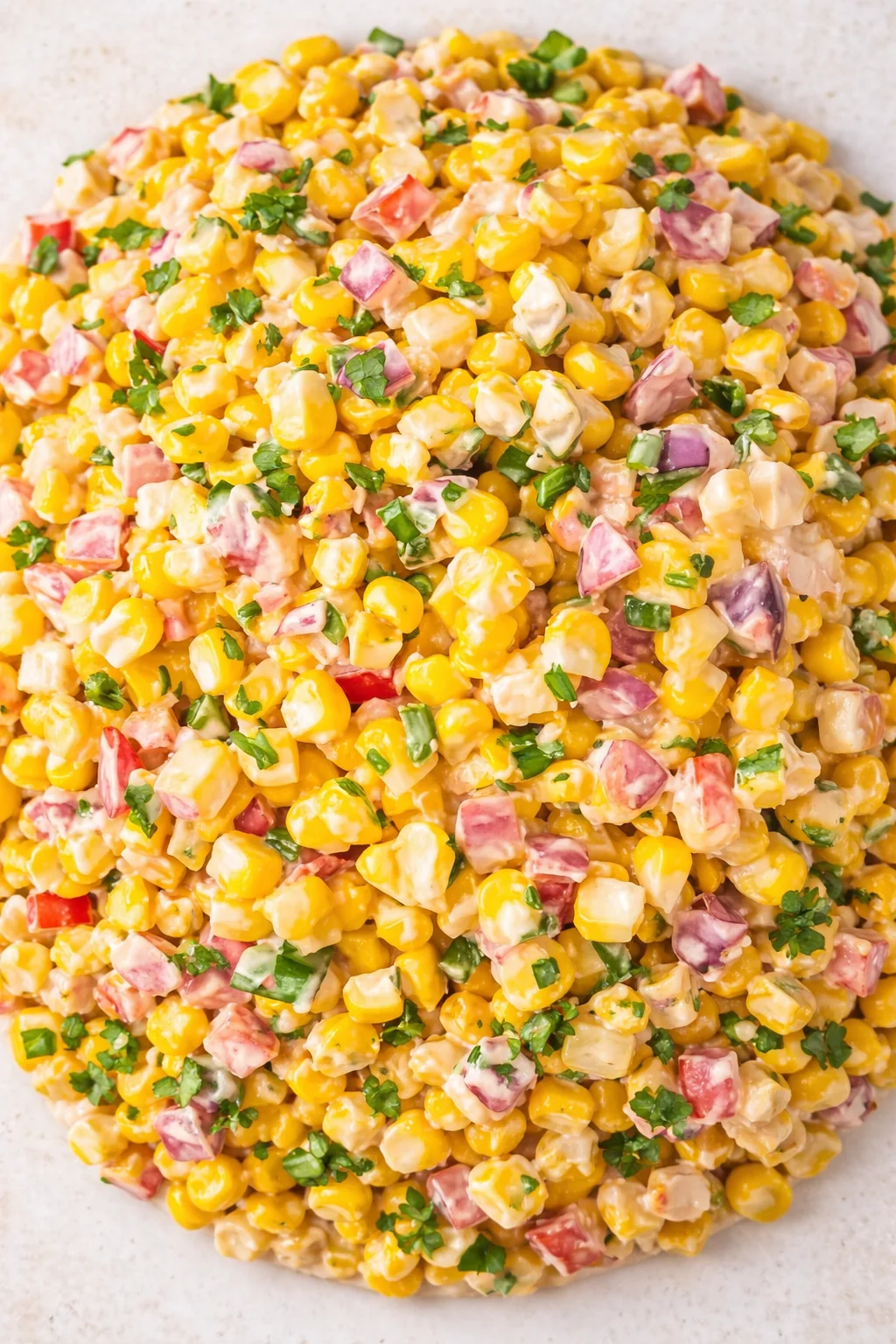 Creamy corn salad with ham cubes, red onion, and green herbs.