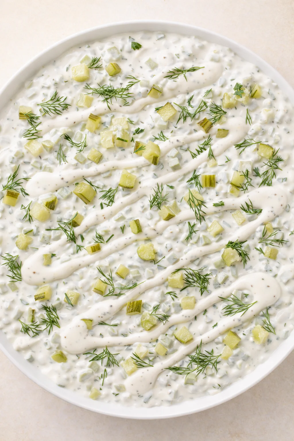 Creamy cucumber-dill dip in a white bowl, garnished with diced cucumber and dill.