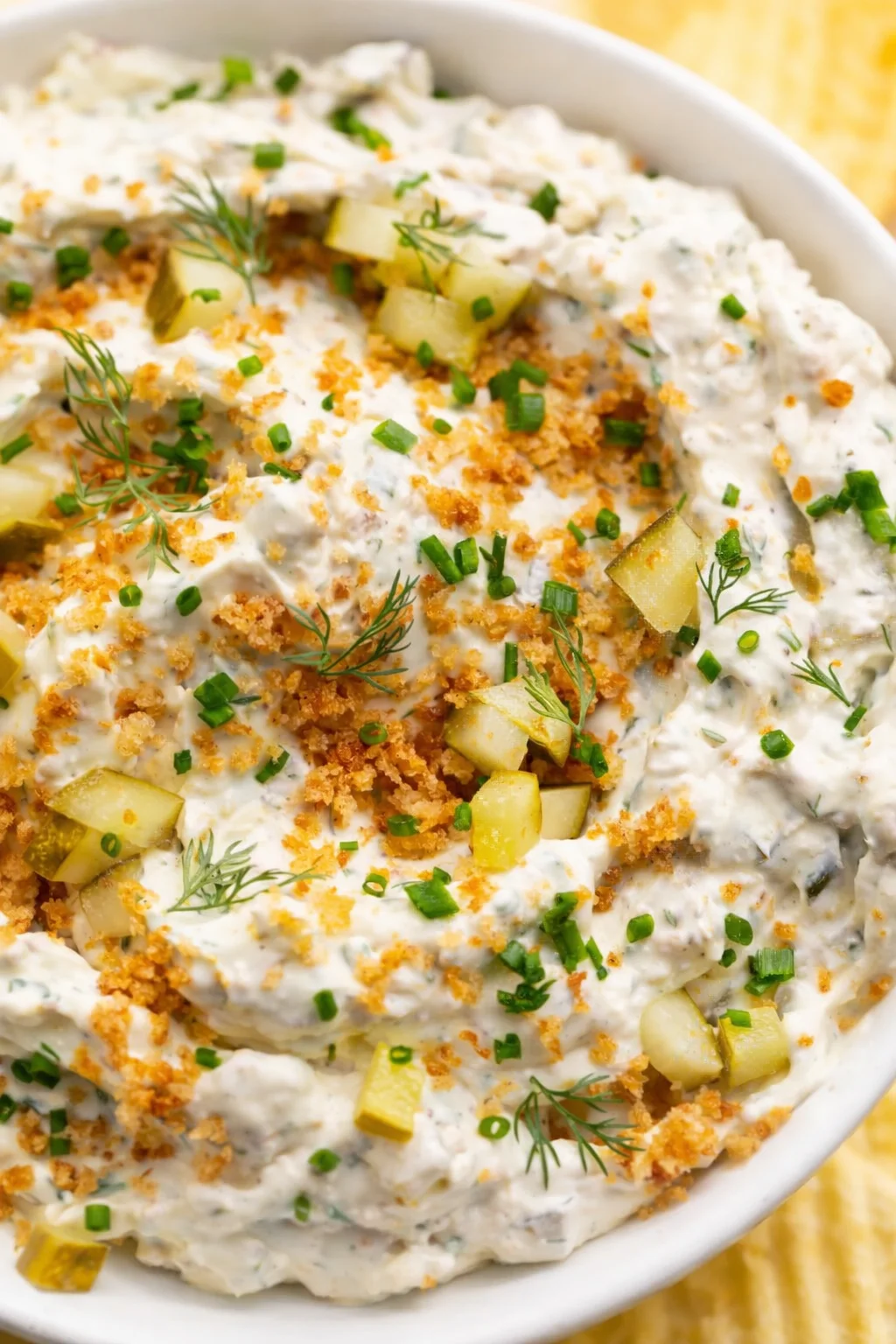 Creamy potato salad with dill, chives, pickles, and crispy breadcrumbs in a white bowl.