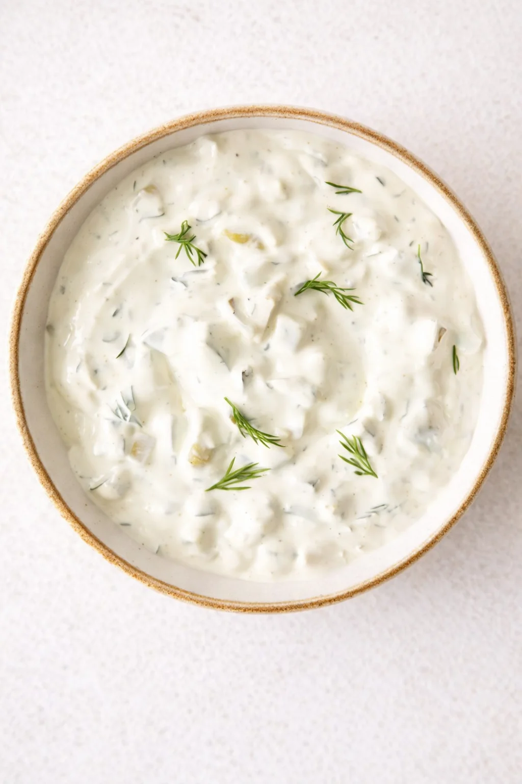 top-down bowl of creamy yogurt-dill sauce garnished with dill fronds