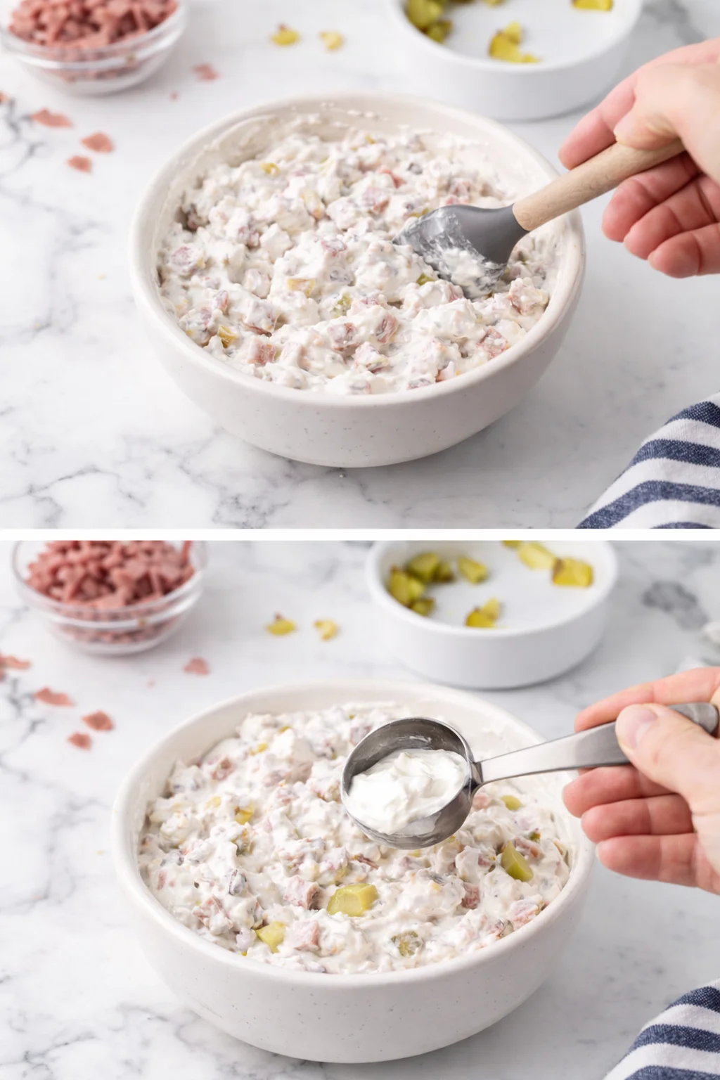 Creamy ham and pickle potato salad being stirred in a white bowl on a marble countertop.