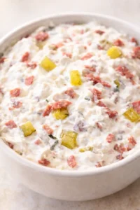 Creamy mayo-based salad with ham and pineapple chunks in a white bowl.