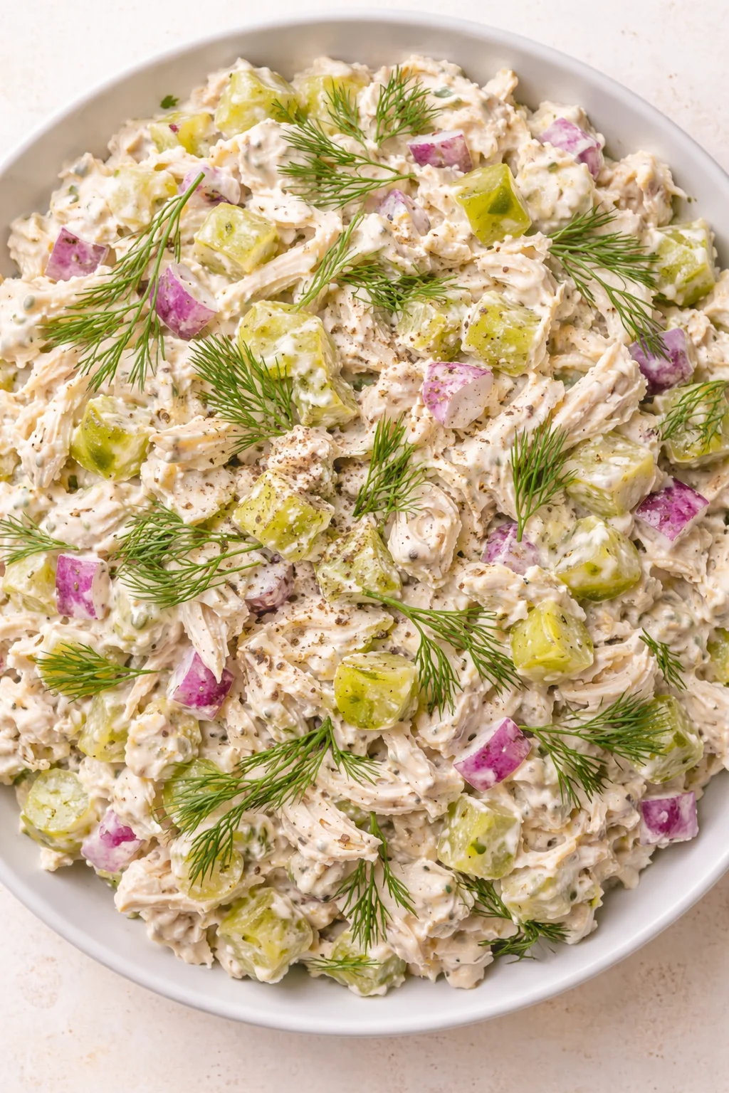 bowl of creamy potato salad with purple and green potatoes and dill garnish