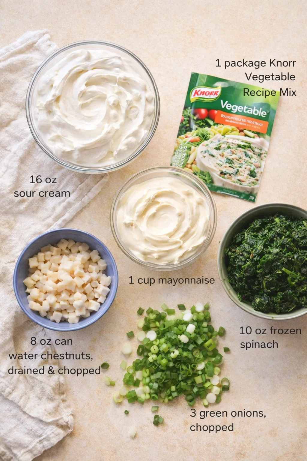 Assorted dip ingredients: sour cream, mayonnaise, water chestnuts, spinach, green onions, and Knorr mix.